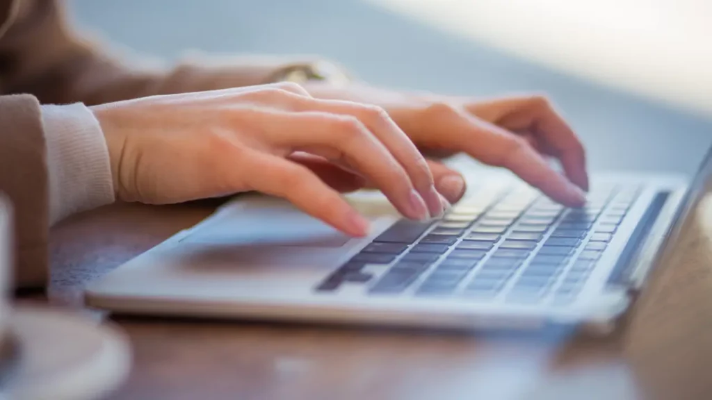 Mulher teclando no computador sobre ia para negócios
